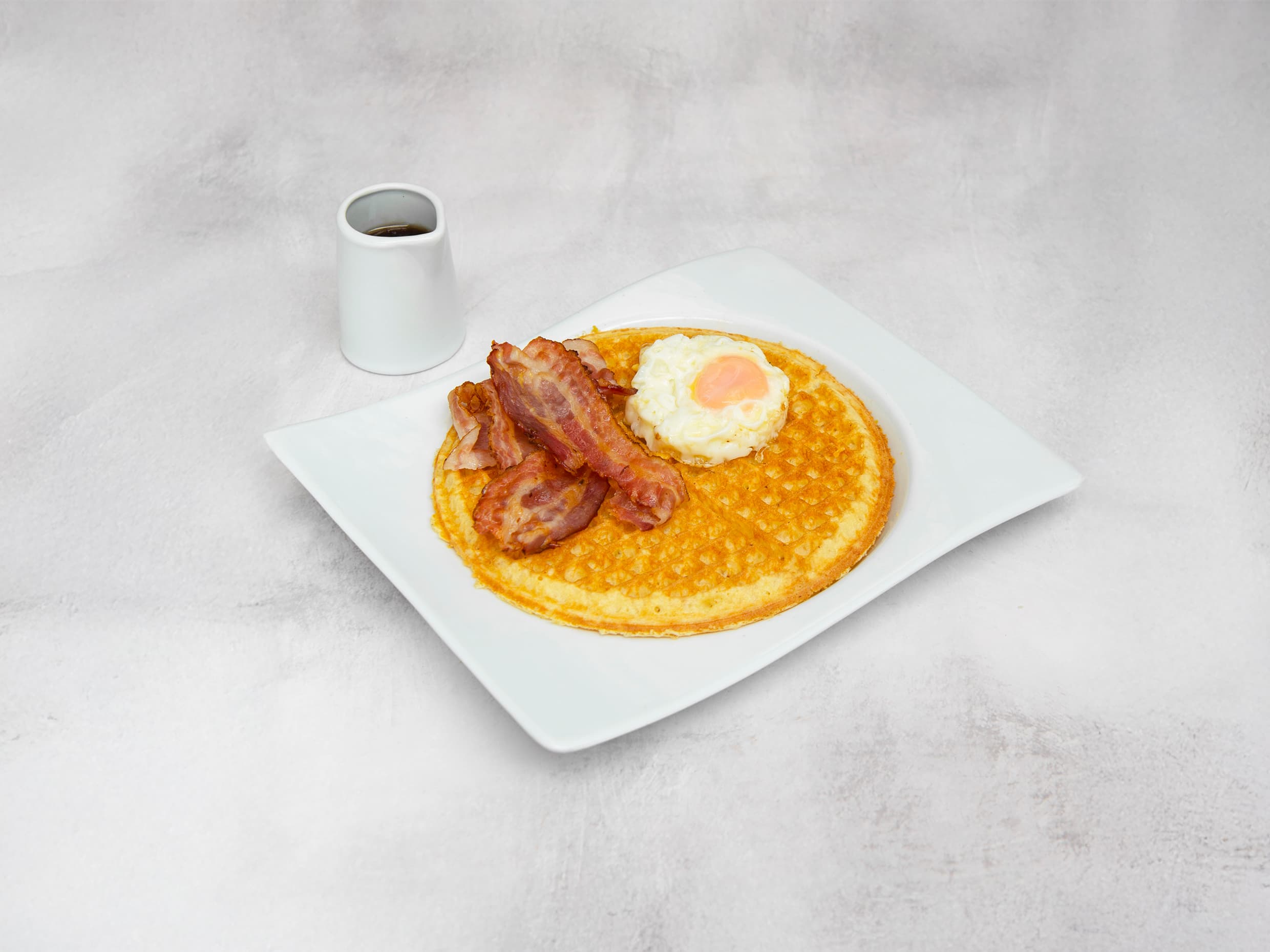 Waffle syrup, huevo frito y tocineta.