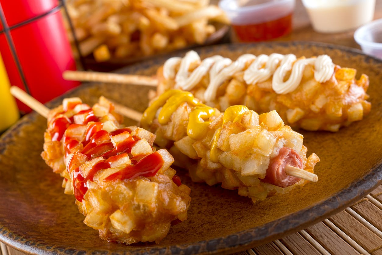 Hot dog estilo coreano servido en banderilla con queso mozzarella