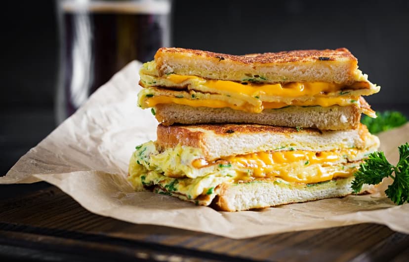 Sándwich tostado con queso amarillo y huevos revueltos
