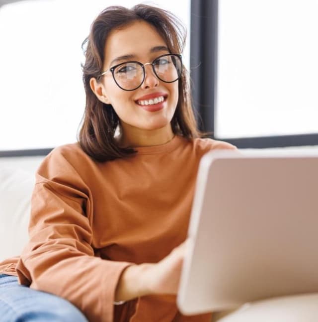 Girl smilling and using a laptop.