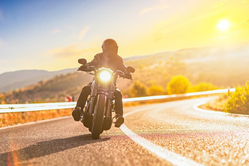 Motociclista manejando en carretera durante el atardecer