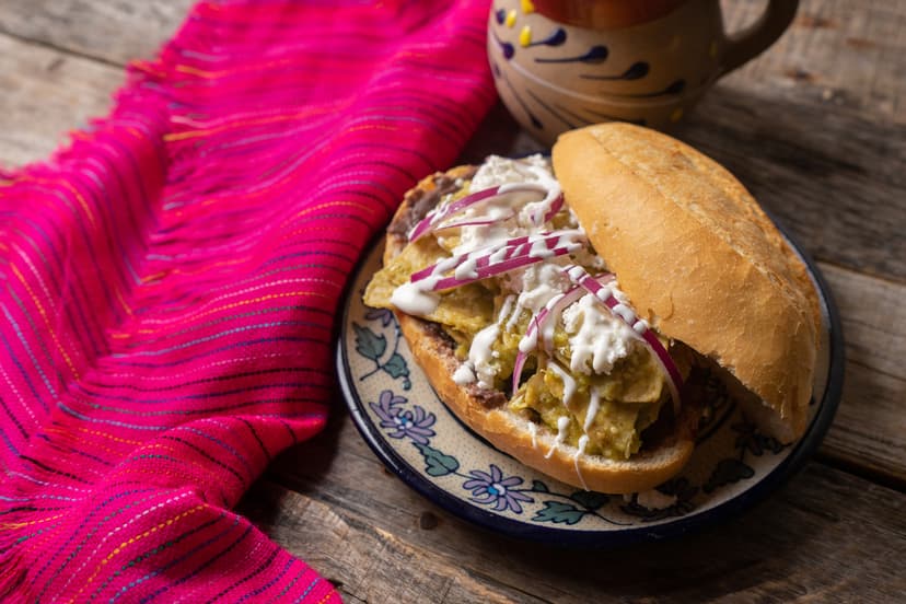 Torta de chilaquiles verdes con crema y cebolla
